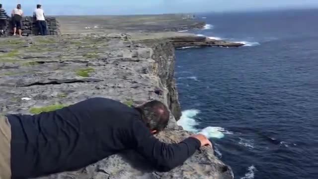 Man crawls through his phobia of heights to get a view of the Atlantic Ocean from the edge of a cliff. 😅